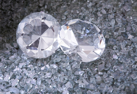 A pair of large plastic diamonds surrounded by glittering fragments.